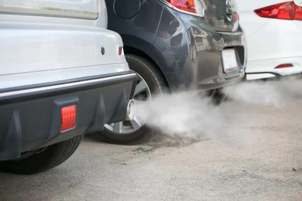 Close-up of back of three cars in a line with smoke coming from tailpipes